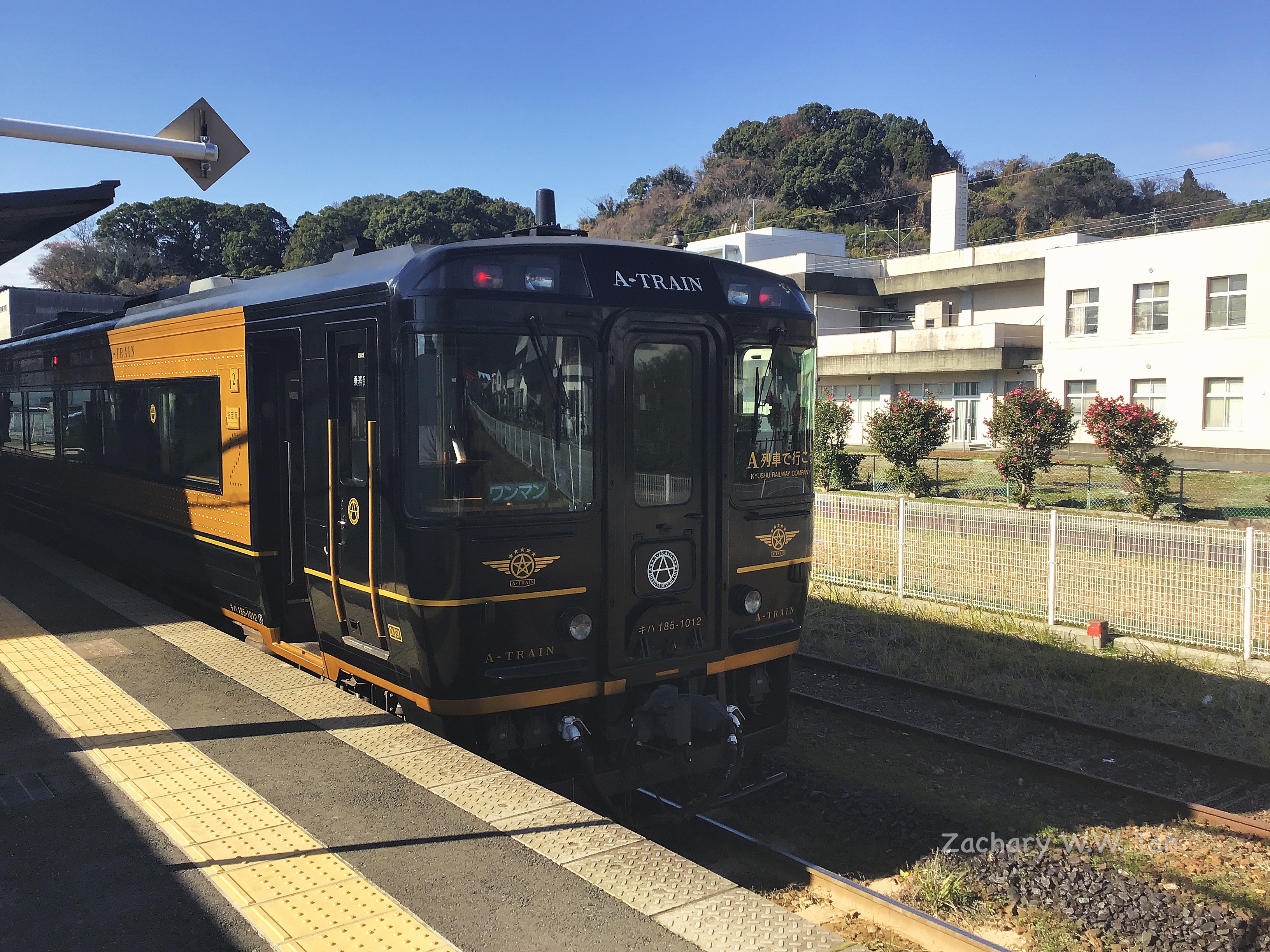 A train at rest at a station platform under sunny conditions