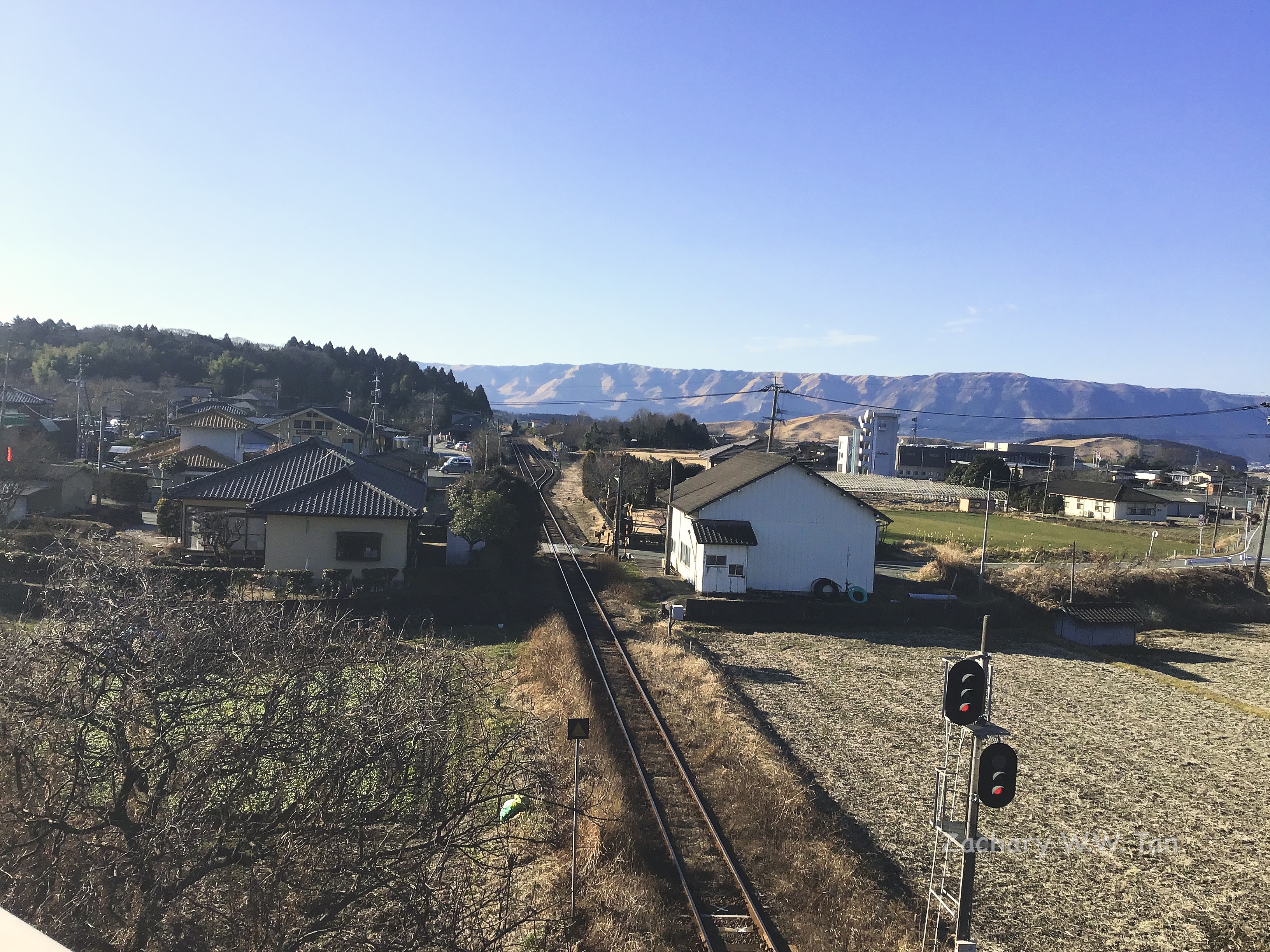 Railway tracks going through Aso Station, with a mountain range in the background