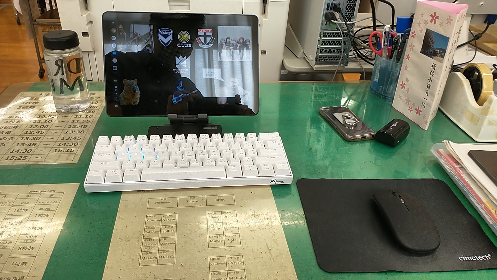 A computer tablet propped on a stand on a desk, with a wireless keyboard and a wireless mouse in front of it